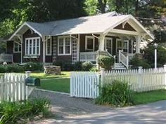 a white picket fence is in front of a red and white house with two windows