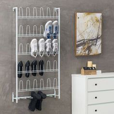 a white shoe rack next to a dresser with shoes on it and a painting hanging above