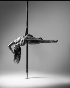 a woman is doing acrobatic on a pole in black and white photo