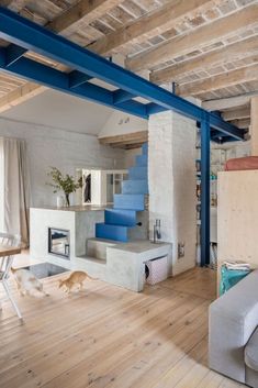 a living room filled with furniture and a fire place under a blue metal stair case