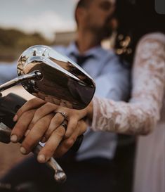 a bride and groom holding hands while riding a motorcycle