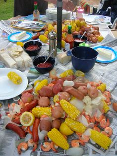 the table is covered with lobsters, corn on the cob, and hot dogs