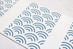 blue and white paper with wavy designs on it sitting on top of a wooden table