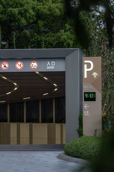 an entrance to a parking garage with no parking signs on the wall and trees in the background