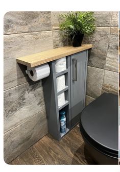 a toilet and cabinet in a bathroom with wood flooring next to a potted plant