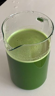 a green liquid in a glass container on a table