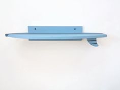 a blue shelf mounted to the side of a white wall with two holes in it