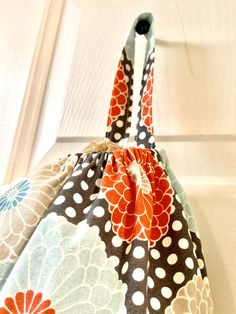 an orange and white flowered purse sitting on top of a door