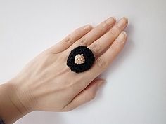 a woman's hand with a black crochet flower ring on top of it