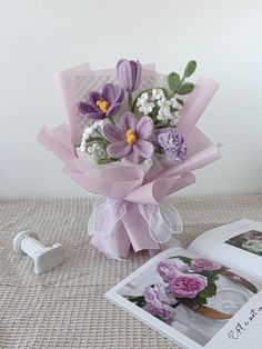 a bouquet of flowers sitting on top of a table next to an open photo album