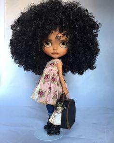 a doll with curly hair holding a suitcase