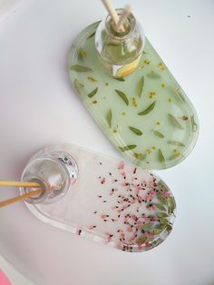 two glass dishes on a white table with flowers in them and a yellow toothbrush holder