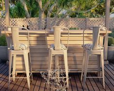 three white chairs sitting on top of a wooden deck next to a planter filled with flowers