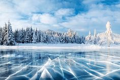 the frozen lake is surrounded by snow covered trees and ice - capped water, with blue skies