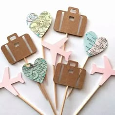 several pieces of luggage and heart shaped stick on a white table with map pins in the shape of hearts