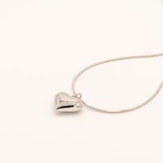 A timeless piece featuring a polished heart pendant on a delicate snake chain. The smooth, dimensional heart catches light from every angle for a simple yet striking effect. Specifications: Finish: White gold platedCore: Titanium steelSize: 41 cm chain + 5 cm extenderClosure: Lobster clasp Silver Stainless Steel Chain Necklace For Valentine's Day, Everyday Metal Open Heart Necklace, Everyday Open Heart Metal Necklace, Valentine's Day Silver Stainless Steel Chain Necklace, Everyday Metal Charm Necklace With Heart Pendant, Everyday Metal Heart Pendant Charm Necklace, Snake Chain Heart Necklace For Gifts, Silver Stainless Steel Heart Pendant Chain Necklace, Silver Stainless Steel Heart Pendant Necklace