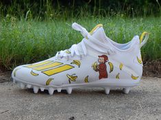 a pair of white and yellow soccer cleats with cartoon characters on them sitting in the grass