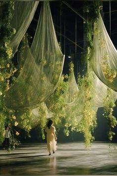 a woman is walking through an open space with sheer curtains hanging from it's ceiling