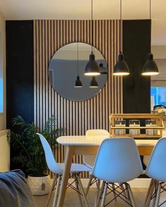 a dining room table with four chairs and a round mirror on the wall