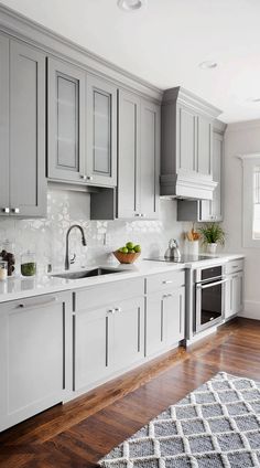 a kitchen with gray cabinets and white counter tops, hardwood floors, and a rug on the floor