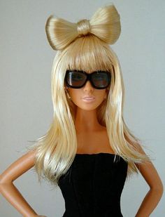 a barbie doll wearing sunglasses and a blonde wig with a bow on it's head