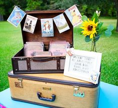 an open suitcase sitting on top of a table next to a sunflower and postcards