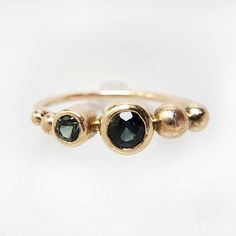 This is a one of a kind 14k gold ring with two deep blue green brilliant cut Madagascan sapphires. A pairing with gold accent beads creates an asymmetrical organic piece that is sure to be a stunner. Make this piece a diamond-alternative engagement ring, treat yourself to something special, or invest in a family heirloom that is sure to be passed down for generations. The sapphires appear deep blue to green, and change colors in different lighting due to refraction- sometimes even appearing blac Diamond Alternative Engagement Ring, Alternative Engagement Ring, Diamond Alternatives, Alternative Engagement Rings, Gold Accent, 14k Gold Ring, Family Heirloom, Gold Filled Jewelry, Polish Jewelry