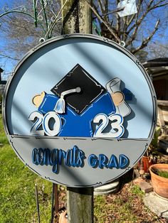 a blue and silver sign with a graduation cap on it's back that says congratulations grad