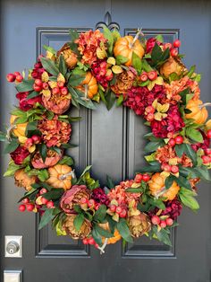 a wreath is hanging on the front door with flowers and leaves around it in fall colors