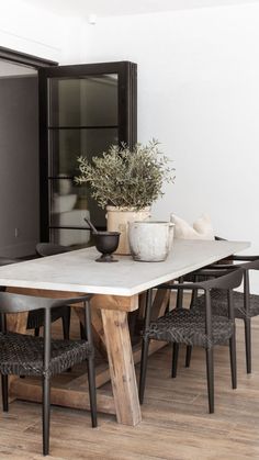 a dining room table with chairs and a potted plant sitting on top of it