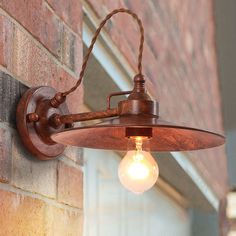 an old fashioned light fixture on the side of a brick building with a bulb hanging from it