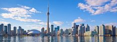 the skyline of toronto is reflected in the water on a sunny day with blue skies and white clouds