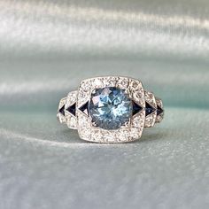 A magnificent 1.21-carat round-cut aquamarine is placed in prongs on a geometric gemstone ring. The aquamarine ring is flanked by a row of triangular French cut sapphires, which are also set on the stepped shoulders. Around the shoulders and set around the sapphires and aquamarine are round brilliant cut diamonds.  This ring contains roughly 0.45 carats of diamonds in total. The total carat weight of the sapphires is approx 0.22 handcrafted in a platinum ring that features an openwork under-gall Luxury Gia Certified Aquamarine Ring, Gia Certified Blue Art Deco Jewelry, Blue Art Deco Jewelry Gia Certified, Light Blue Round Cut Diamond Jewelry, Aquamarine Gemstone Diamond Ring In Round Cut, Aquamarine Diamond Ring With Round Cut, Art Deco Diamond Topaz Ring, Modern Sapphire Jewelry Gia Certified, Modern Sapphire Jewelry With Gia Certification