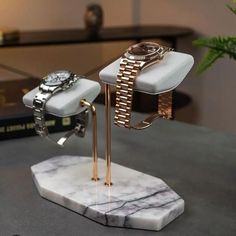 a watch on a stand with a marble base and gold plated bracelets attached to it