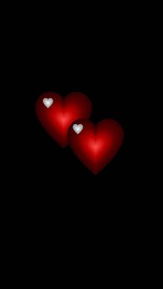 two red hearts sitting on top of each other in the middle of a black background