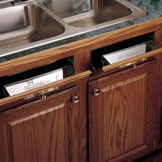 two metal sinks sitting next to each other on top of a wooden cabinet under a sink