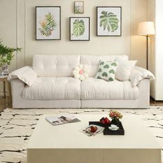 a living room filled with white furniture and pictures on the wall above it's coffee table