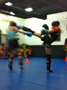 two women are practicing kickbox in an indoor gym