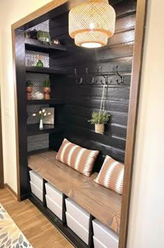 a room with black walls and wooden shelves filled with white storage bins under a light fixture