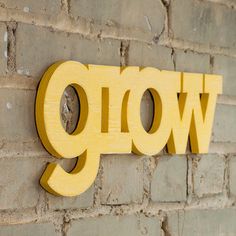 a close up of a sign on a brick wall with the word glow painted on it