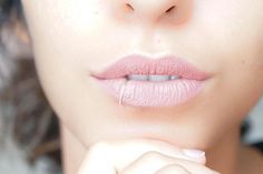 a close up of a woman's face with her hand on her chin, wearing pink lipstick