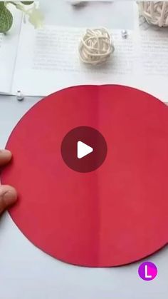 a person is cutting out a red paper circle