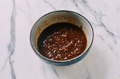 a bowl filled with sauce sitting on top of a marble counter