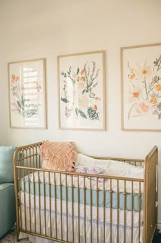 a baby's crib in front of three paintings on the wall