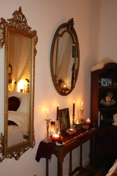 candles are lit in front of a mirror on the wall next to a dresser and bed