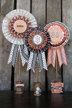 three decorative ribbons on top of each other in front of a wooden wall and fence