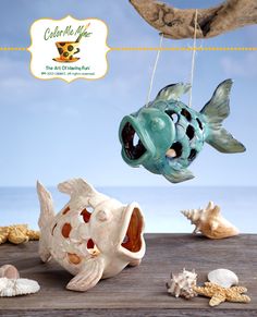 a ceramic fish hanging from a string next to seashells