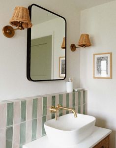 a bathroom sink sitting under a mirror next to a wall mounted faucet with lights on it