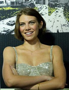 a woman standing with her arms crossed in front of a cityscape background and smiling