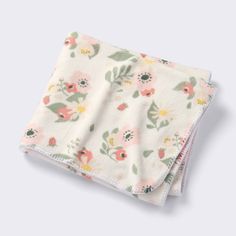 a white blanket with pink and green florals on it, folded in two rows